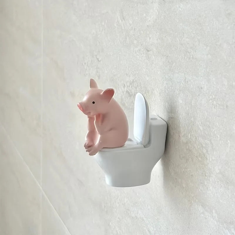 A Little Pig Figurine Sitting on the Toilet - A Decorative Item, Placed on the Table or Wall, on a Home Office Desk - q